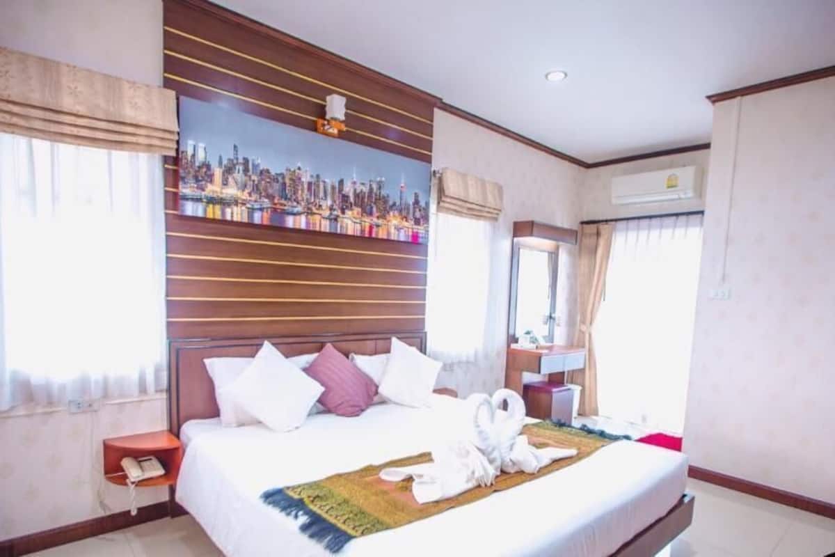 A hotel room with a bed, a cityscape painting, a telephone, and a window with curtains.