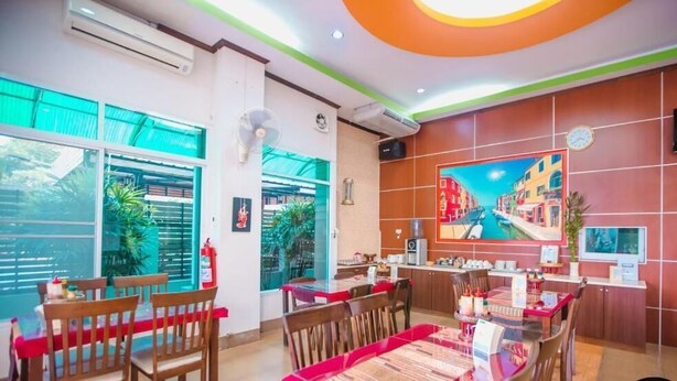 A dining area with wooden chairs and tables, a large window with a view, and a wall-mounted television. - Bander Hotel (Phu Khiao)