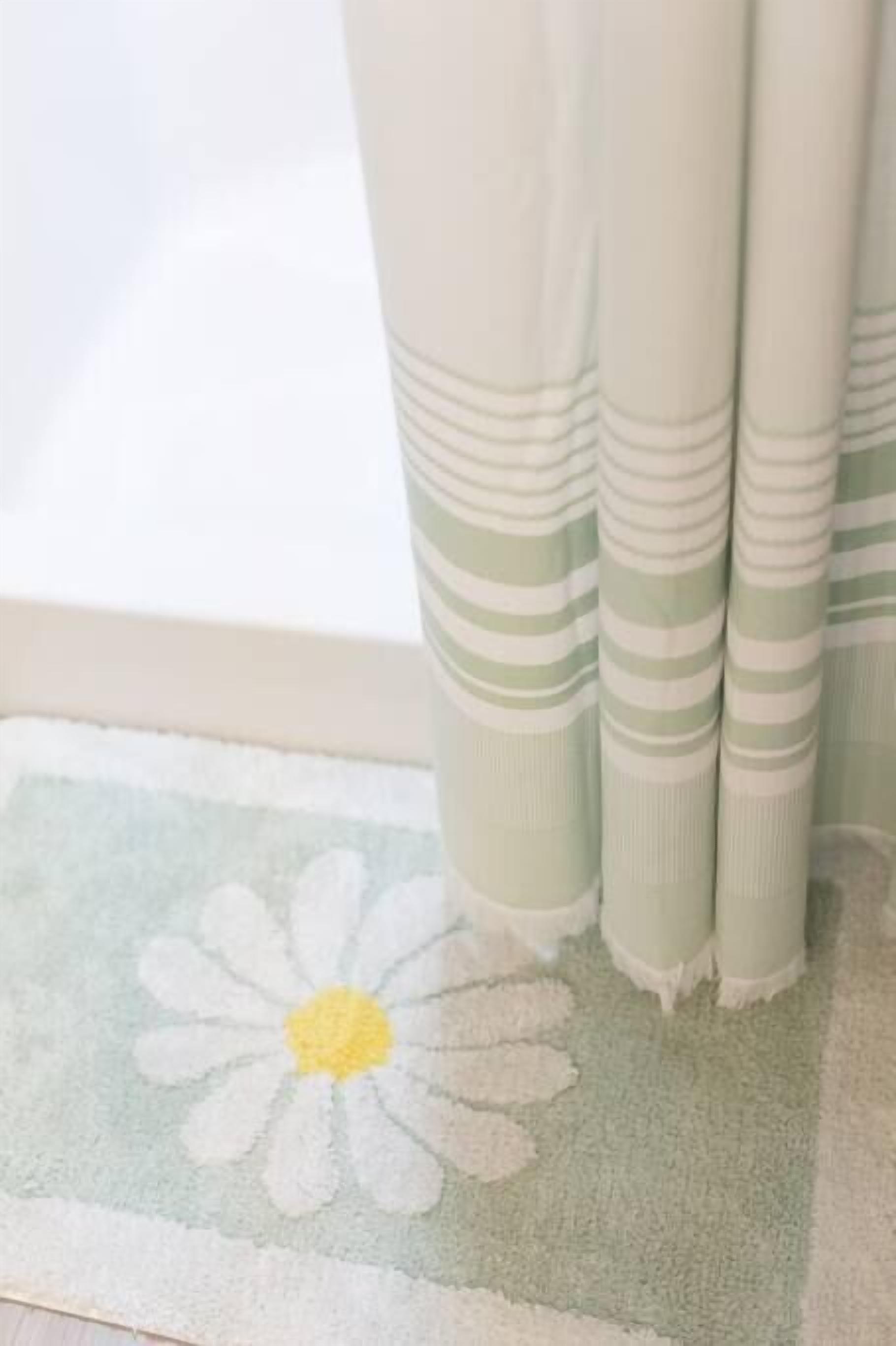 Una ventana con cortina que presenta un estampado de margaritas y diseño a rayas.