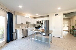 A modern kitchen with white cabinets, stainless steel appliances, and a central island.