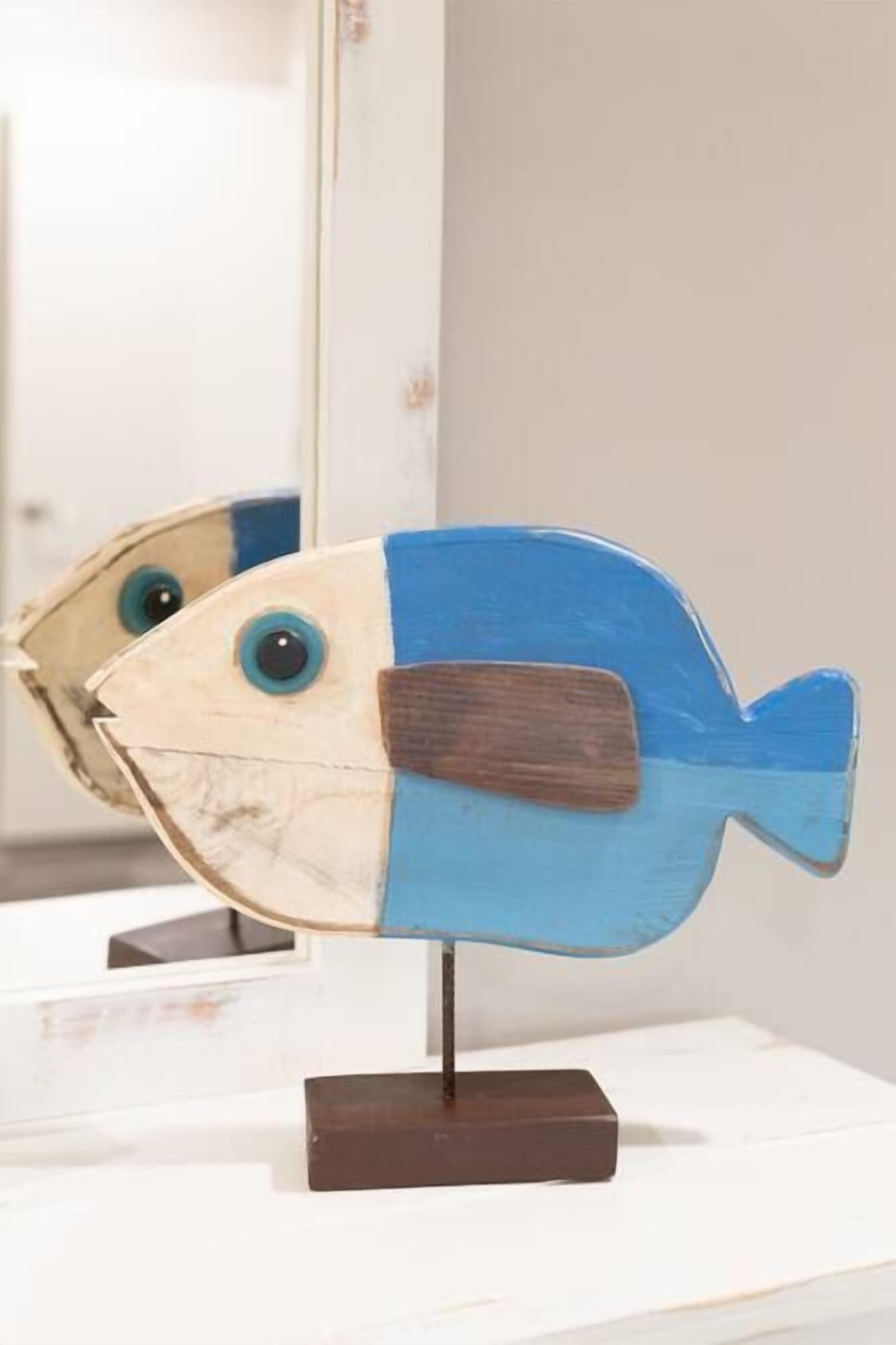 A fish-shaped sculpture with a blue and beige body, mounted on a dark base.