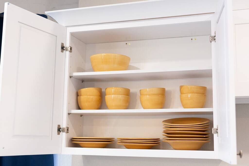A white cabinet with multiple shelves containing various bowls and plates.