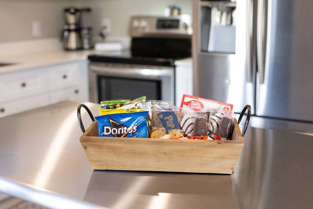 Un piano di lavoro in cucina con un cesto di legno pieno di snack.