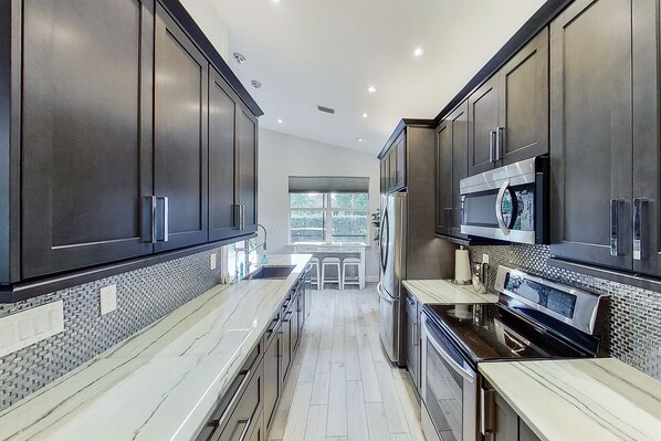 Features a spacious layout with a central island, stainless steel appliances, and a tiled backsplash.