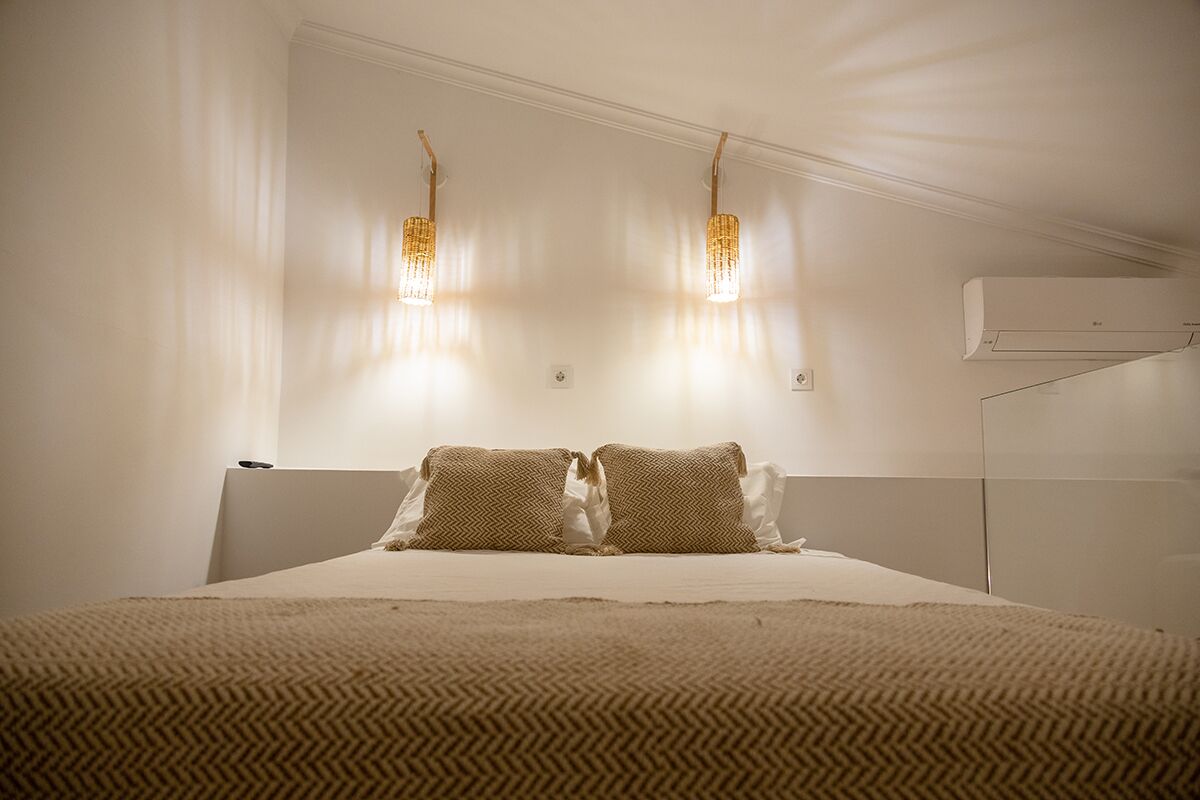 A bedroom with a bed, two wall-mounted lights, and an air conditioner.