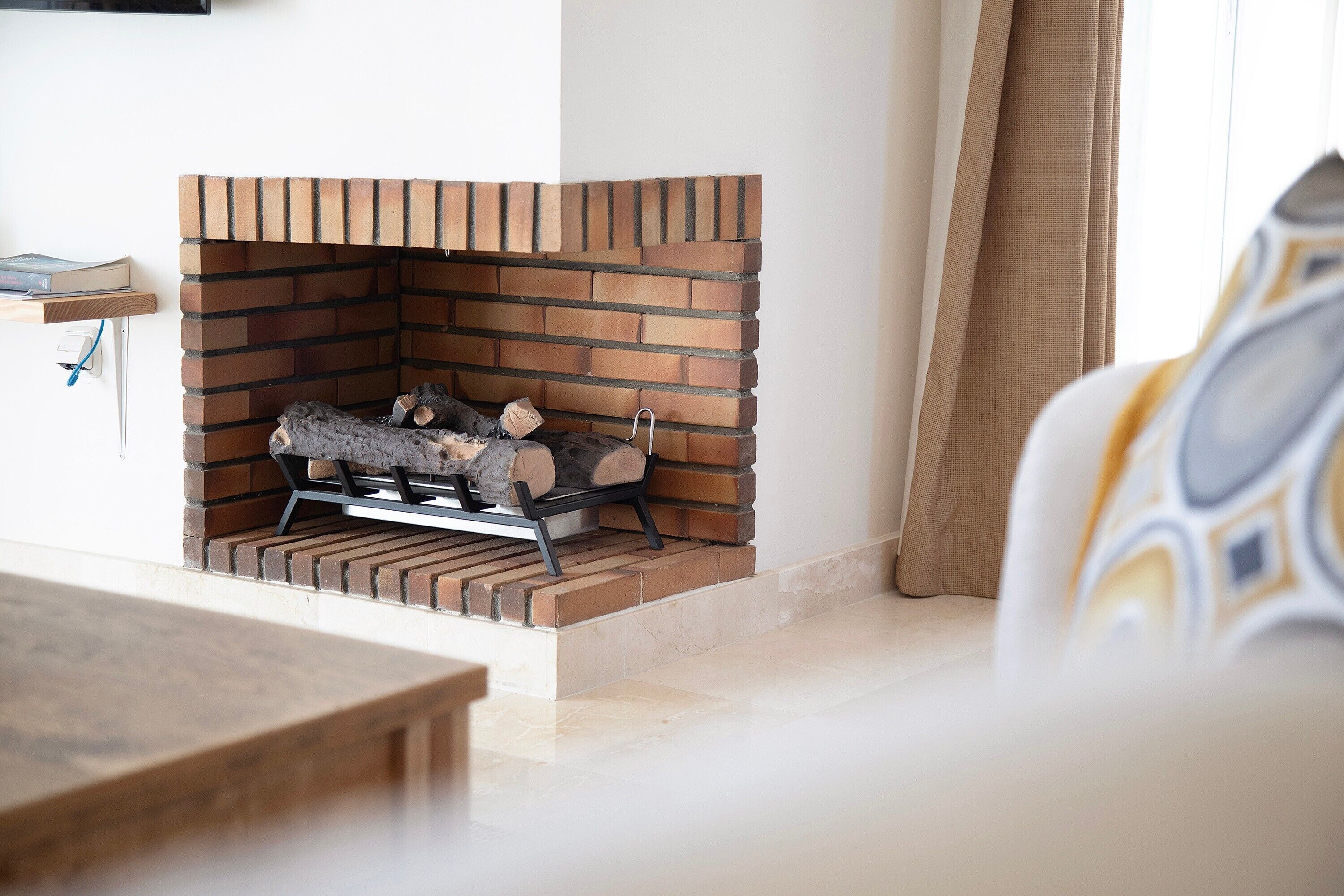 Une cheminée avec un foyer en briques, une cheminée en bois et un porte-bûches.