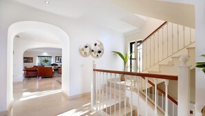 Un vaste espace de vie comprenant un escalier, un canapé et un élément décoratif mural.