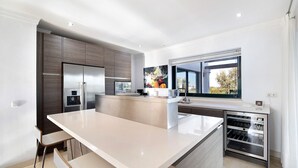 Une cuisine moderne dotée d’un îlot central, d’appareils électroménagers intégrés et d’une grande fenêtre.