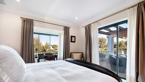 Une chambre d’hôtel dot ée d’un grand lit, d’un bureau et d’un balcon aménagé avec du mobilier d’extérieur.