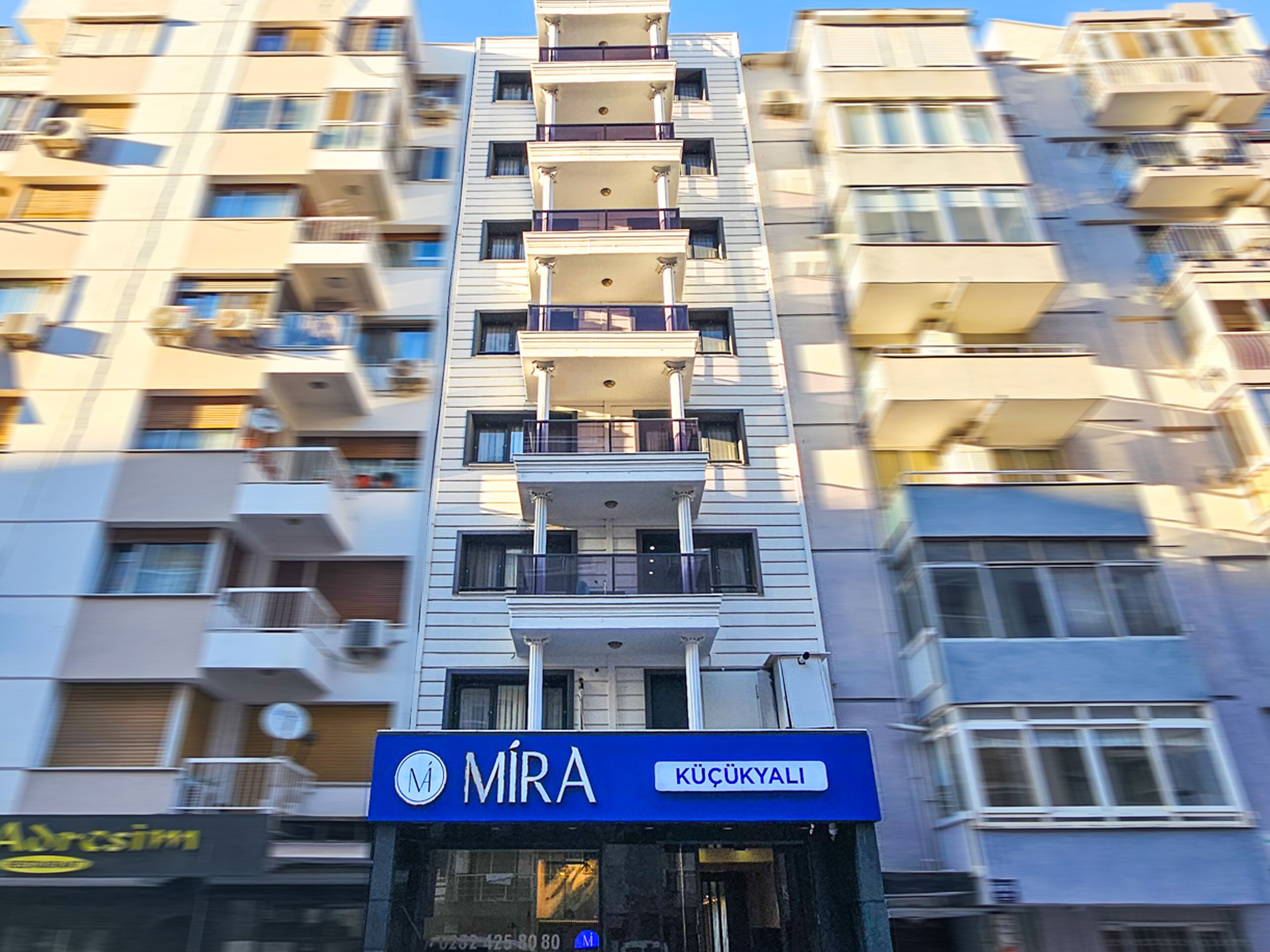 Un edificio de varios pisos con balcones y un letrero que dice 'MIRA' en la planta baja.