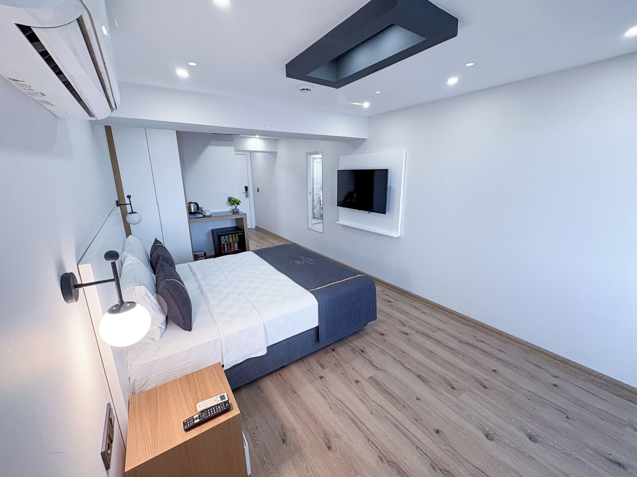 Un dormitorio moderno con cama, mesita de noche y televisor en la pared.
