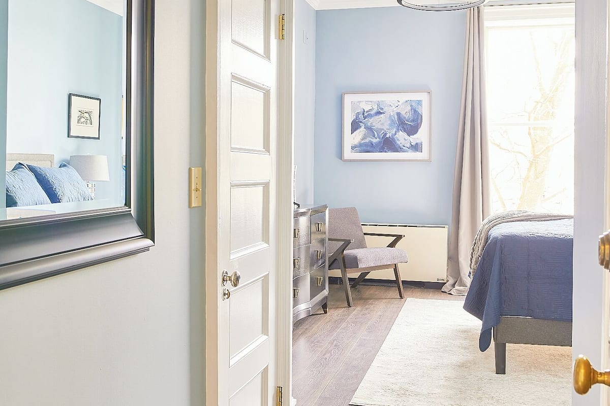 A bedroom with a bed, a desk, a chair, and a dresser.