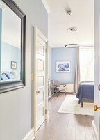 Um quarto com cama, escrivaninha, cadeira e cómoda.