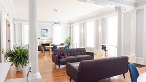 A spacious living room with a gray sofa, blue chairs, and a white fireplace.