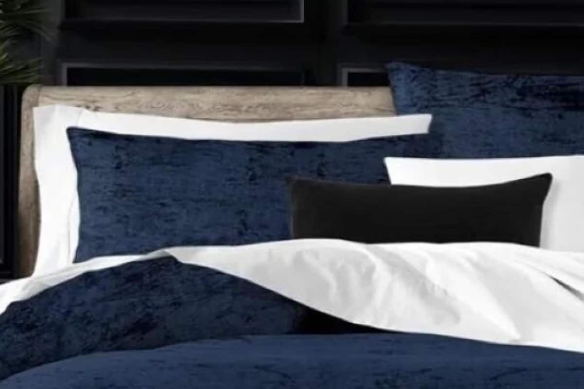 A bed with a dark blue headboard and white bedding.