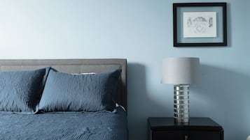 A bedroom with a bed, a nightstand, a lamp, and a framed picture on the wall.