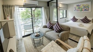 A hotel room with a bed, a sofa, a small table, and a TV. - The Title Naiyang Residence (Sa Khu)