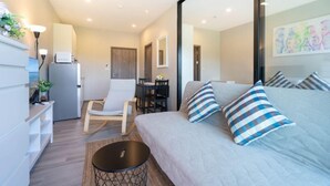 A modern living room with a sofa, striped pillows, a coffee table, and a dining area with chairs and a table. - The Title Naiyang Residence (Sa Khu)