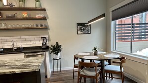 Una cocina moderna con isla integrada, suelo de madera y comedor con mesa redonda y sillas.