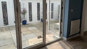 A room with a sliding glass door leading to an outdoor area with a tiled patio. - Fabulous apartment for 2 in Llansteffan (Llansteffan)
