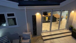 A patio area with a seating arrangement and a sliding glass door leading to an outdoor space. - Fabulous apartment for 2 in Llansteffan (Llansteffan)
