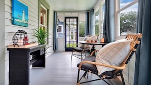 A cozy porch with a chessboard, wicker chairs, and a painting of a lighthouse. - Tranquil Avondale Home, Walkable to Food & Shops! (Jacksonville)