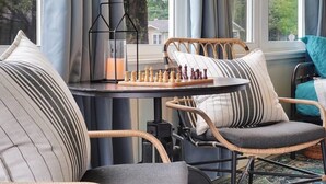 A cozy outdoor seating area with wicker chairs, a chessboard, and a table with a candle. - Tranquil Avondale Home, Walkable to Food & Shops! (Jacksonville)