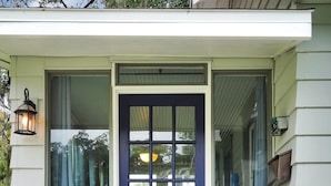 A front view of a house with a dark blue door, two windows on either side, and a small porch with steps leading up to the door. - Tranquil Avondale Home, Walkable to Food & Shops! (Jacksonville)