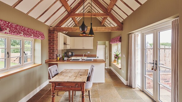 Una cocina con una mesa de madera, una pared de ladrillo y una ventana.