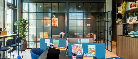A modern office space with cubicles, a coffee table with a laptop, and a bookshelf with books and decorative items.