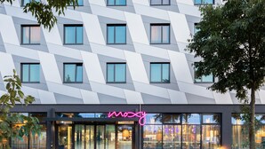 Un edificio moderno con fachada geométrica y un letrero de neón que dice "mozy".