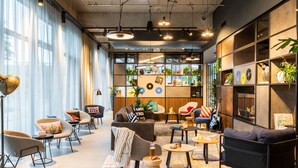 Un área de estar moderna con asientos, una mesa de centro y una estantería llena de libros y objetos decorativos.