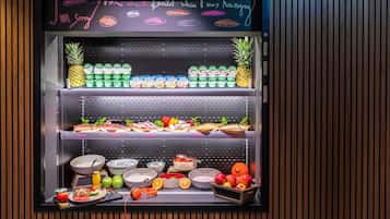 Un refrigerador exhibe diversos alimentos, entre ellos frutas, yogur y sándwiches.