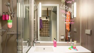 A modern bathroom with a glass shower enclosure, a white sink, and a mirror.