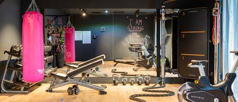 A gym with various exercise equipment, including a punching bag, dumbbells, and an exercise bike.
