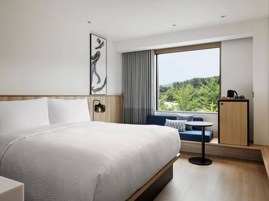 Een moderne hotelkamer met een groot bed, een zithoek met uitzicht en een televisie.
