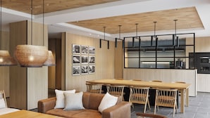 A modern kitchen with wooden cabinets, a dining area with a wooden table and chairs, and a leather sofa with cushions.