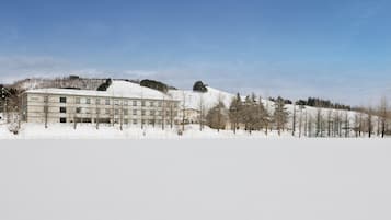 A hotel with a modern design, located on a snow-covered hill with a clear sky.
