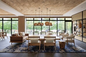A modern living room with a large window, a wooden ceiling, and a dining area with chairs and a table. - Fairfield By Marriott Hyogo Kannabe Highland (Toyooka)