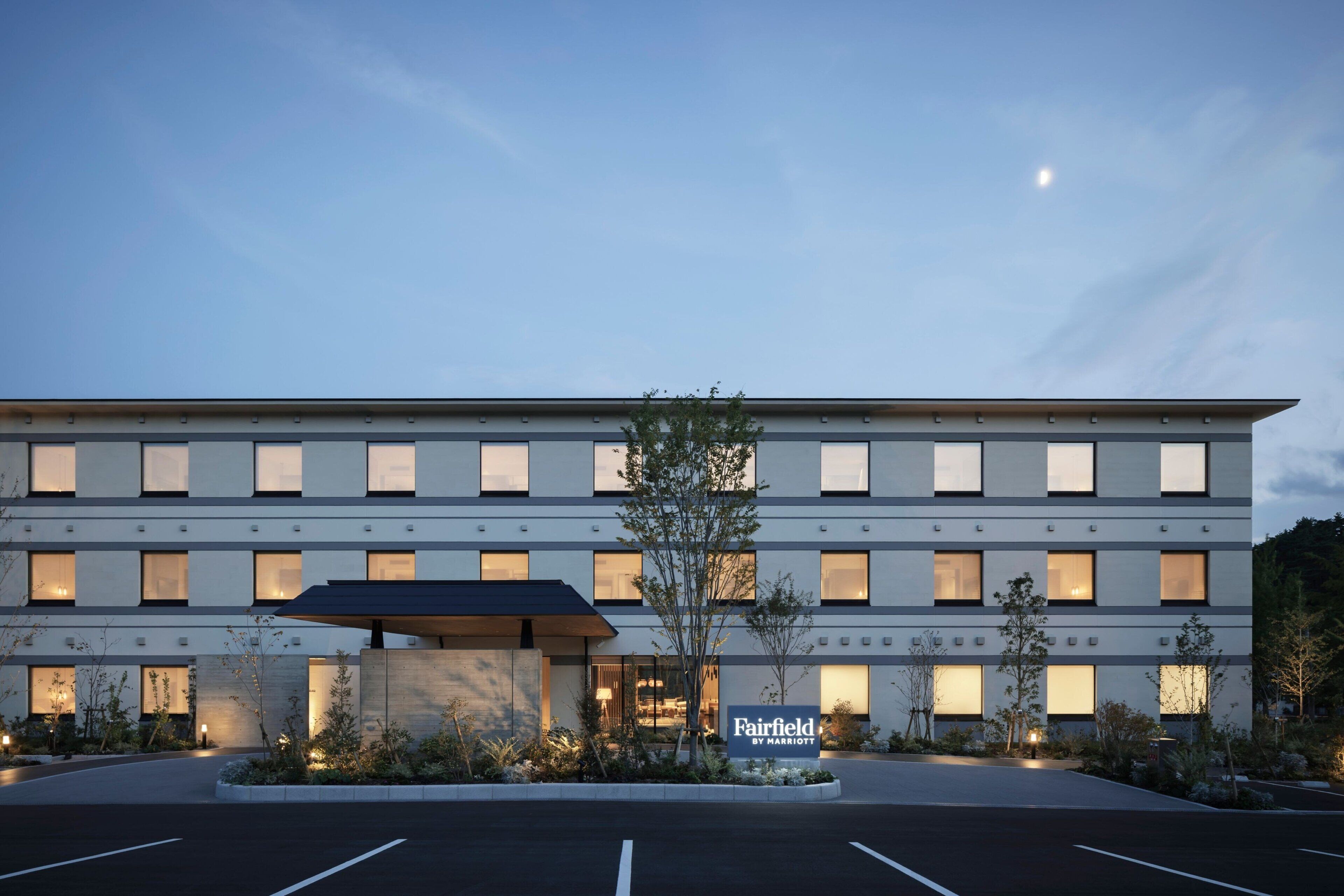 A modern hotel with a flat facade, multiple windows, and a parking lot.