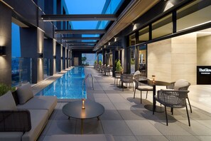 A modern outdoor pool area with a glass-enclosed pool, lounge seating, and a bar area. - Four Points By Sheraton Suwon (Suwon)