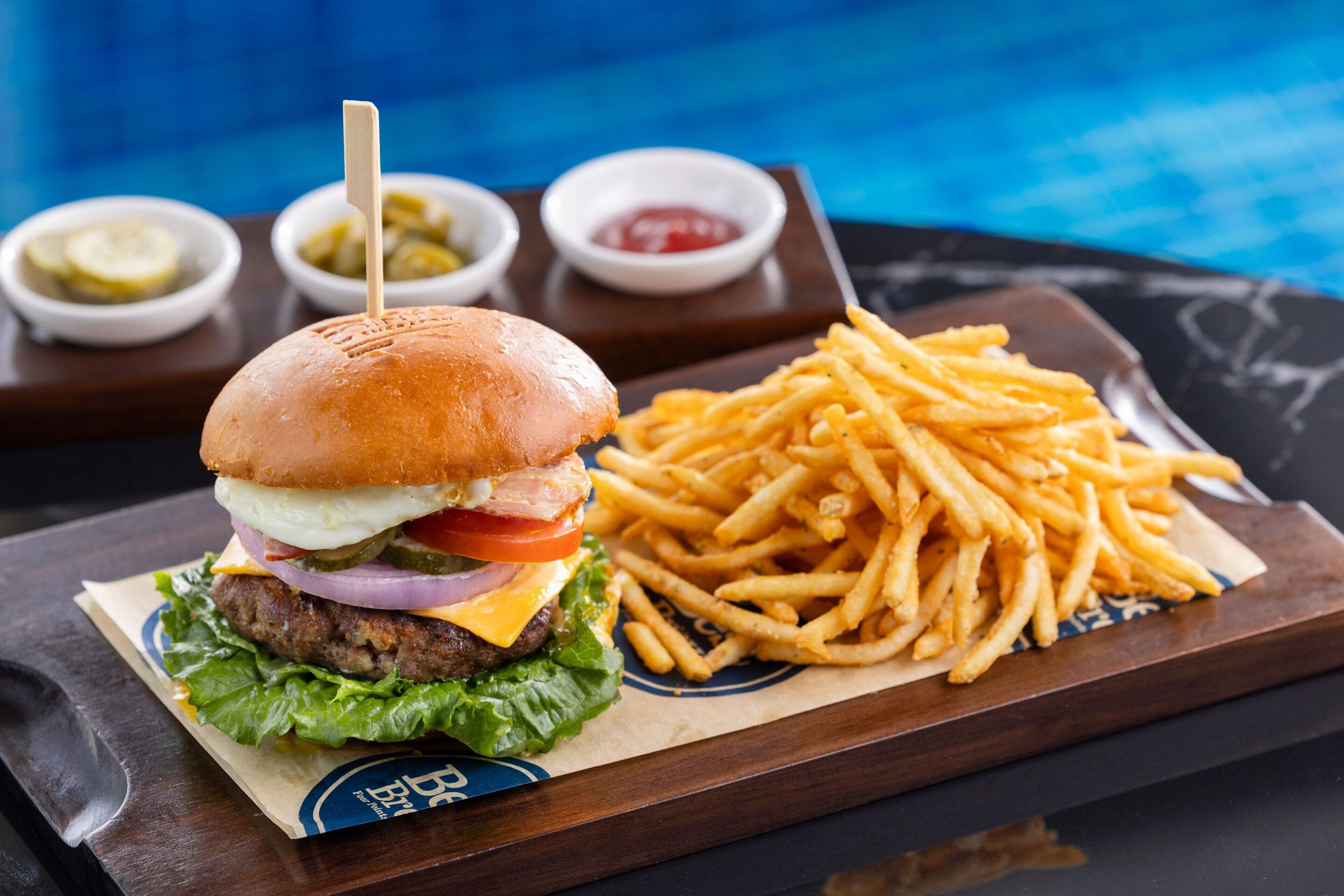 Una hamburguesa con papas fritas y condimentos sobre una bandeja.