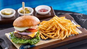 A burger with fries and condiments on a tray.
