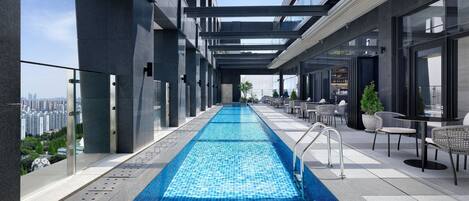 Una piscina en la azotea con vistas a la ciudad, mobiliario exterior y un diseño arquitectónico moderno.