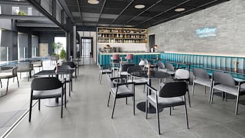 A modern bar area with a poolside seating arrangement, a bar counter with a variety of bottles, and a sign reading "The Glow Poolside Bar".