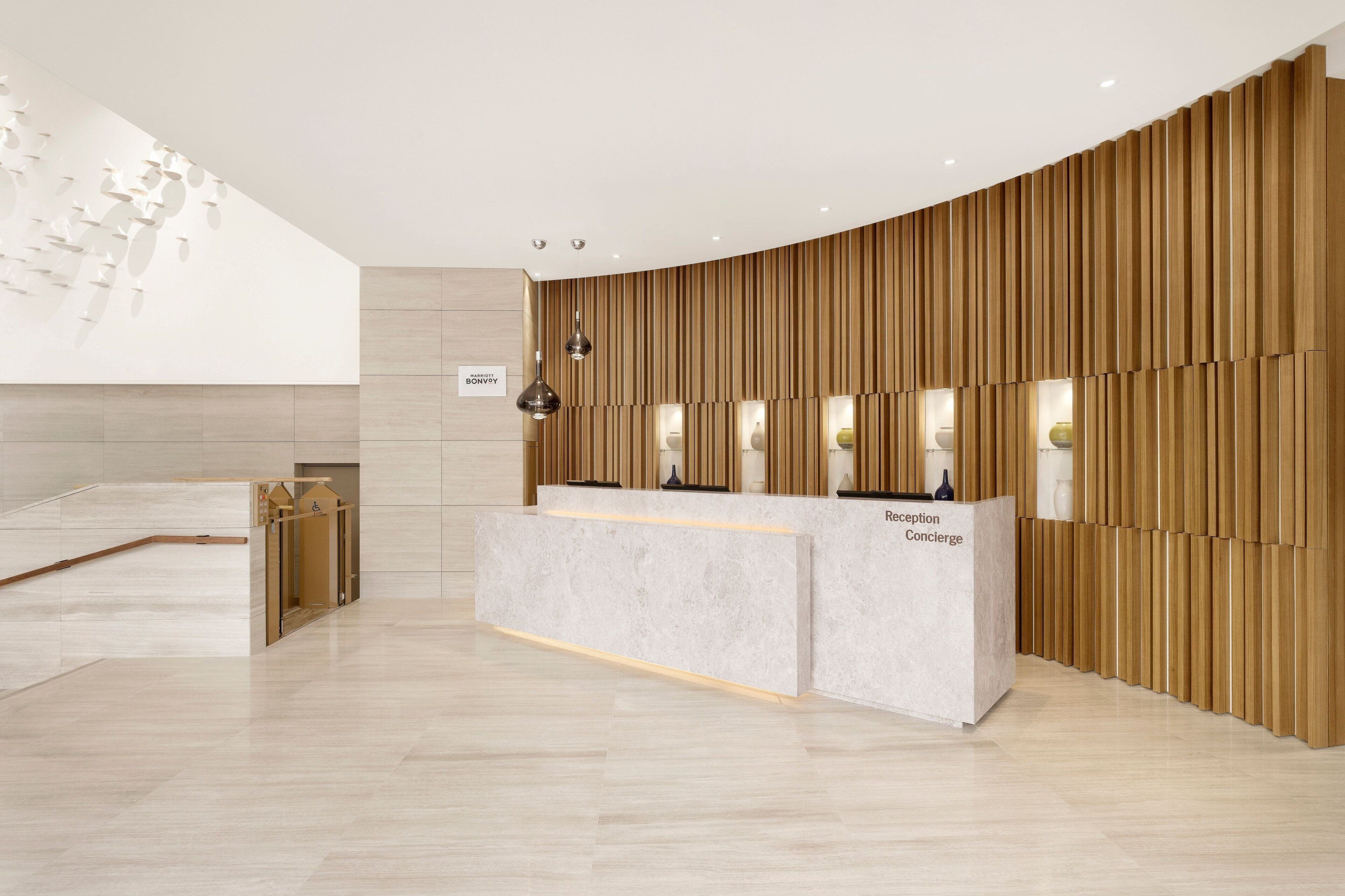 Una zona de recepción con un mostrador curvo, paneles de madera e iluminación colgante.