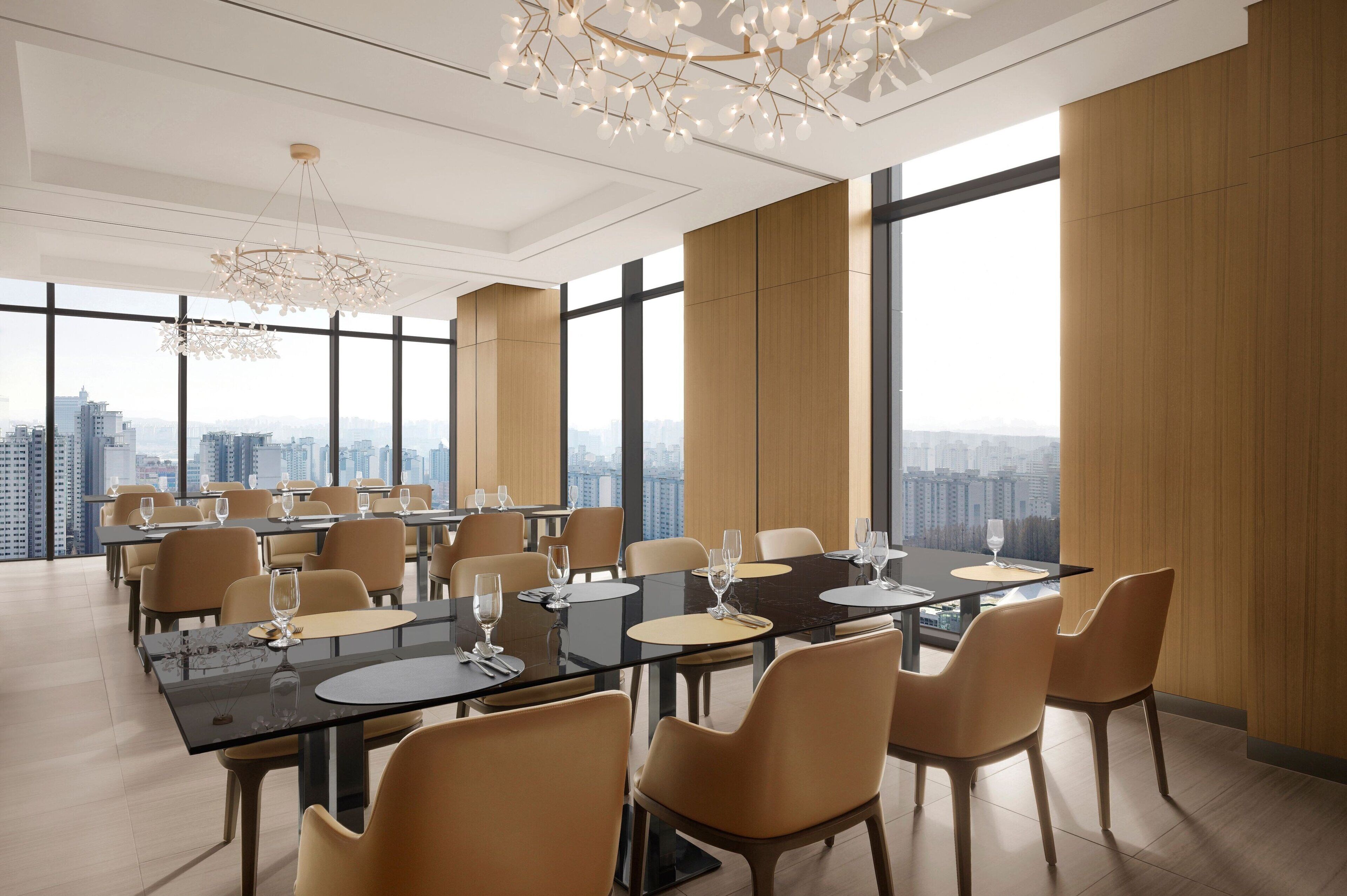 Un comedor moderno con amplios ventanales, techos altos y luminarias contemporáneas.