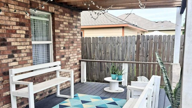 A covered patio with a wooden deck, a white bench, a small round table, and a potted plant. - Beautiful house close to the sea (Corpus Christi)