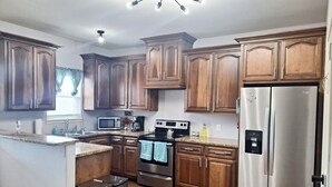 A modern kitchen with wooden cabinets, stainless steel appliances, and a granite countertop. - Beautiful house close to the sea (Corpus Christi)