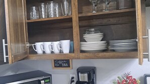 A kitchen with wooden cabinets, a microwave, a coffee maker, and a sign indicating a coffee bar. - Beautiful house close to the sea (Corpus Christi)